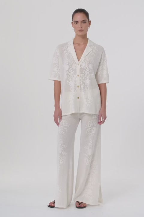 Model moves in full-length crochet pants made from a hemp cotton blend, showing fluid drape and breathable texture. Styled for warm-weather layering with matching shirt.