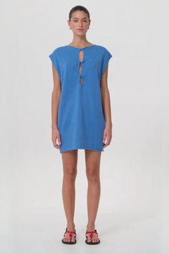 Model in motion wearing reversible shift mini dress with twist detail in pacific blue linen–cotton blend—highlighting soft drape, structure and breathability for seasonal transitions.
