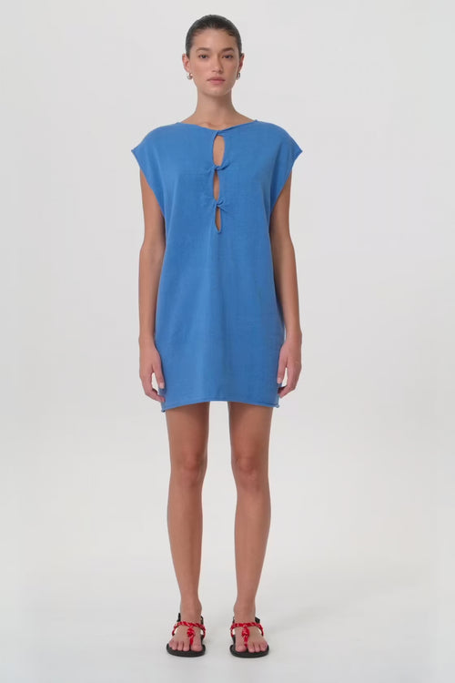 Model in motion wearing reversible shift mini dress with twist detail in pacific blue linen–cotton blend—highlighting soft drape, structure and breathability for seasonal transitions.