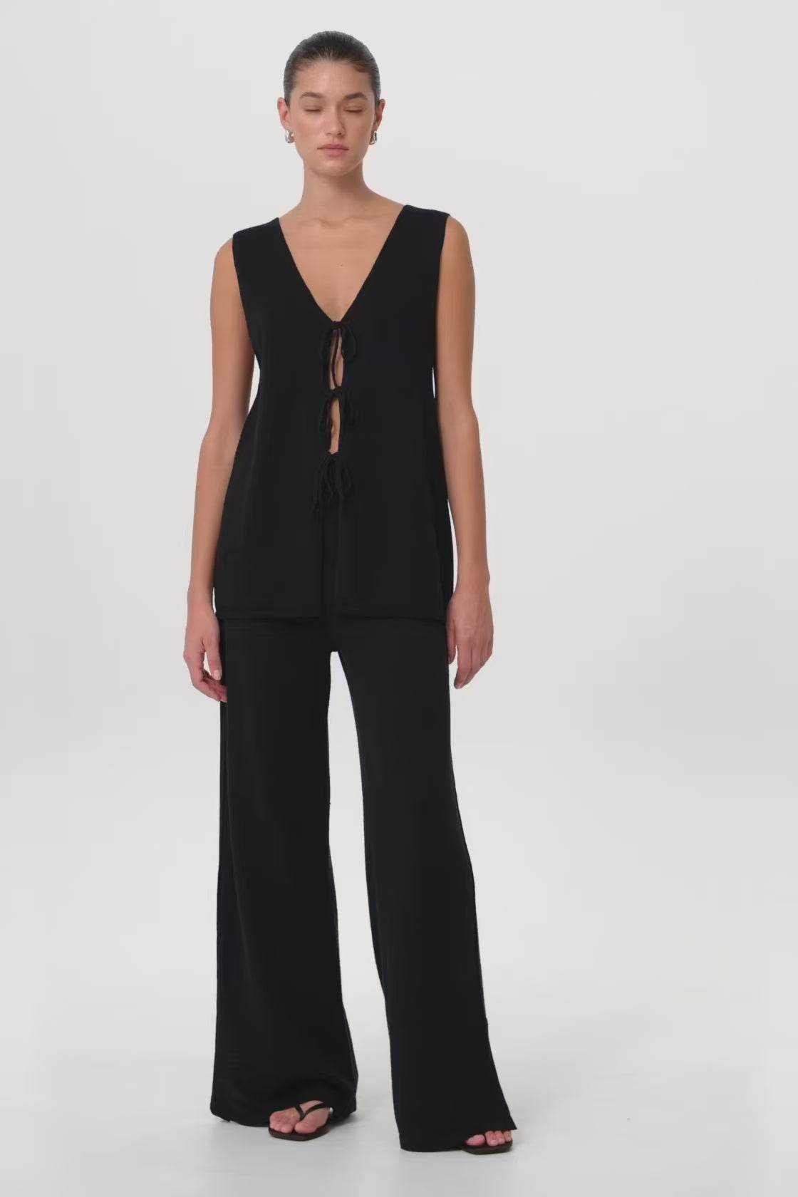 Model in motion wearing wide-leg Poppy Set in breathable black linen–cotton blend—highlighting pleat detail, relaxed fit and soft structure through the leg.