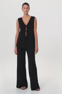 Model in motion wearing wide-leg Poppy Set in breathable black linen–cotton blend—highlighting pleat detail, relaxed fit and soft structure through the leg.