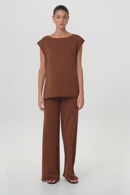Model moves in clay wide-leg knit pant and matching top, showing natural drape, side pleats, and relaxed fit in motion.