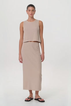 Model in motion wearing taupe knit tank and matching skirt set, highlighting flared hem, rolled edges and breathable movement through seasonal transitions.