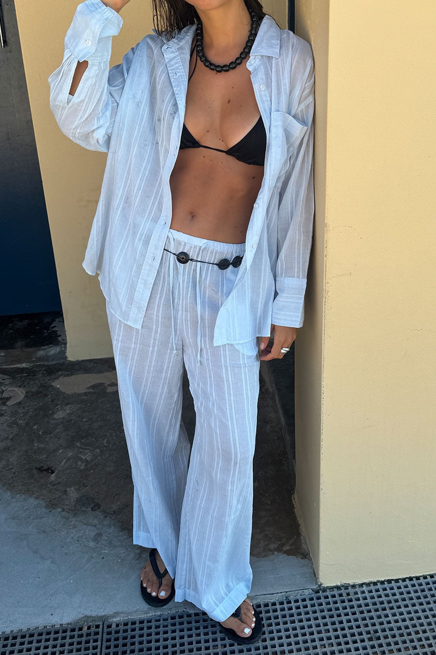 Model in relaxed cotton pants with a soft stripe texture and fluid silhouette, styled with matching shirt.